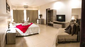 ein großes Zimmer mit einem Bett und einem Fernseher in der Unterkunft Hotel Renascer Ltda in Morrinhos