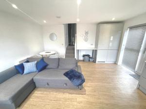salon z szarą kanapą i niebieskimi poduszkami w obiekcie La Fontaine Court Apartments - Aldershot w mieście Aldershot