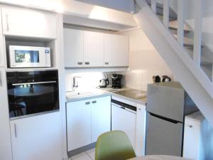 una cocina con armarios blancos y una escalera en Studio mezzanine - LAOUEN, en Sarzeau