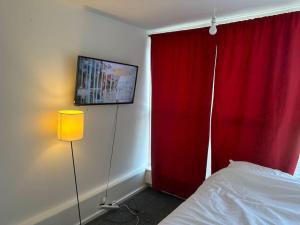 ein Schlafzimmer mit einem roten Vorhang und einem Bett und einer Lampe in der Unterkunft 3bed Rooms Apartment Terrace in Crystal Palace