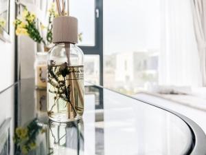 eine Flasche auf einem Glastisch mit einer Blumenvase in der Unterkunft StoneTree - 3 BR with 1 Maids Room Villa in Camelia - Arabian Ranches in Dubai