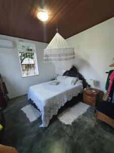 - une chambre avec un lit et un lustre dans l'établissement Chácara Sombra da Mangueira - 150 Mts da Praia, à Itaparica Town