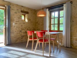 a dining room with a table and red chairs at Le Gîte du Pont de Cause in Saint-Cybranet