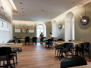 un restaurant avec des tables et des chaises en bois et des personnes assises à table dans l'établissement Hotel St. Josef, à Zurich
