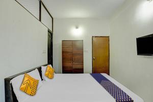 1 dormitorio con 1 cama con almohadas amarillas y azules en SPOT ON Sri Durga Residency Hd Kote, en Mysore