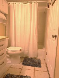 a bathroom with a white shower curtain and a toilet at Sea Club Condo #405 in Clearwater Beach