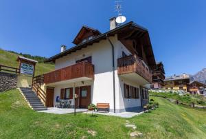 un piccolo edificio bianco con balconi in legno su una collina di Appartamenti Baita Soliva a Oga