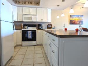 eine Küche mit weißen Schränken und weißen Geräten in der Unterkunft Sea Club Condo #405 in Clearwater Beach