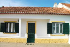 Casa blanca con persianas verdes y puerta en One bedroom house with shared pool furnished terrace and wifi at Santarem, en Santarém