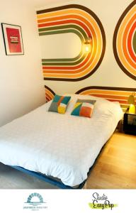 a bedroom with a white bed with colorful pillows at Locations du Grand Pont - Appart hôtel Poitiers - Futuroscope in Chasseneuil-du-Poitou