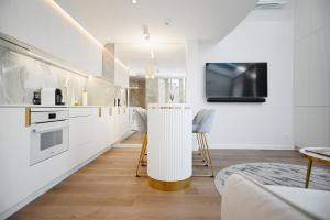 a kitchen with white cabinets and a tv on the wall at Prestige Sopot Residence by 3City Rentals in Sopot