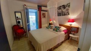 1 dormitorio con 1 cama y 1 silla roja en Bungalow de 2 chambres a Bouillante a 100 m de la plage avec vue sur la mer jardin amenage et wifi, en Bouillante