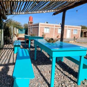 tres mesas de picnic azules frente a un edificio en Salir del Cráter Apart in 