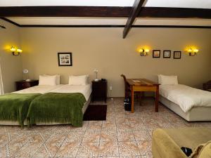 a bedroom with two beds and a table in it at Casa Blanca Boutique Hotel Pension in Windhoek