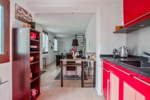 uma cozinha com armários vermelhos e uma mesa numa cozinha em Quiet house with terrace in Nanterre - Welkeys em Nanterre