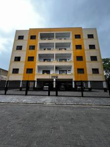 a yellow and white building behind a fence at Apto Espaçoso no Centro de Ubatuba - 3 quartos, 2 vaga garagem,2 banheiros,Cozinha Completa in Ubatuba