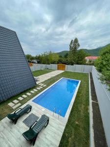 a backyard with a swimming pool and two lawn chairs at Qafqaz Eminent Chalet in Gabala