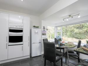 a kitchen with a white refrigerator and a table with chairs at Ty Cerrig in Pwllheli