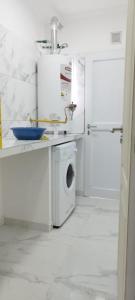 uma cozinha branca com uma máquina de lavar roupa e um lavatório em Maktub Alojamiento em San Antonio Oeste
