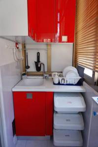 uma pequena cozinha com armários vermelhos e um lavatório em CasAmelia em Messina