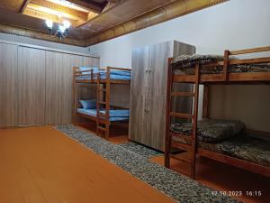 a room with three bunk beds and a wooden floor at INJIR Hostel in Dushanbe