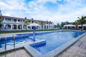 a swimming pool with an umbrella in front of a building at Silver Sand Eco Resort !! Beachfront !! in Mandarmoni