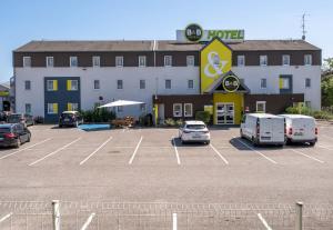 un hôtel avec des voitures garées dans un parking dans l'établissement B&B HOTEL Annecy Argonay, à Argonay