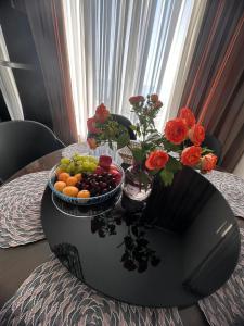 a table with a bowl of fruit and flowers on it at Prestigio Sea view apart in Batumi