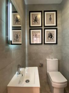 a bathroom with a toilet and a sink and framed pictures at Stylish Valletta Apartment in Valletta