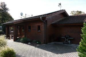 a small wooden cabin with a brick patio at Holzblockhaus, Eifel in Oberkail
