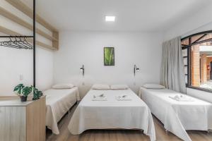 a room with three beds and a window at Elite Hotel in Florianópolis