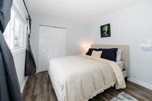 a white bedroom with a bed and a window at Blue Caribou Bungalow in Penticton