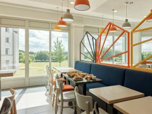 - une salle à manger avec des tables, des chaises et des fenêtres dans l'établissement B&B HOTEL près de Disneyland Paris, à Magny-le-Hongre
