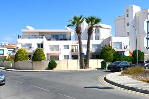 a street in front of a white building with palm trees at Отдыхайте с удовольствием in Paphos
