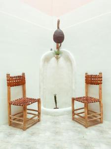 3 sillas de madera y una cúpula de cristal con una planta. en DesArt Appartment, en Tamraght Ouzdar