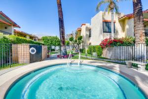 a swimming pool with a fence and palm trees at Resort Perks, Private Patio Palm Springs Condo! in Palm Springs