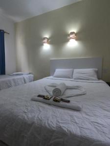 Una cama blanca con toallas encima. en Pousada Cabufa, en Cabo Frío