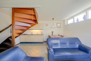 uma sala de estar com um sofá azul e uma escada em Vakantiehuis Guja - Callantsoog em Callantsoog