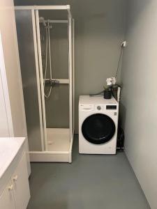 eine Waschmaschine im Bad mit Dusche in der Unterkunft Leilighet i rolig gate med utsikt og gratis parkering in Tromsø