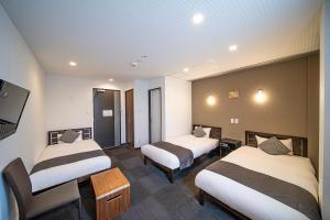 a hotel room with two beds and a flat screen tv at HOTEL STATE TENNOJI in Osaka