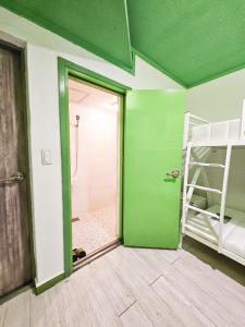 Habitación con pared verde, ducha y puerta en Travelers A Korea Hostel en Seúl