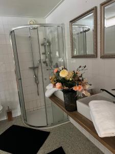 ein Badezimmer mit einer Dusche und einer Vase aus Blumen auf der Theke in der Unterkunft La Dolce Vita Suites in Leeuwarden