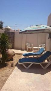 - deux chaises longues sous un parasol sur la terrasse dans l'établissement Diar Karim Djerba, à Midoun