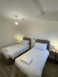 duas camas num quarto com lençóis brancos e toalhas em The Dormy House em Tenby