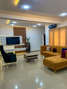 1118 Serenity Residence في أبوجا: غرفة معيشة مع كنب وتلفزيون بشاشة مسطحة