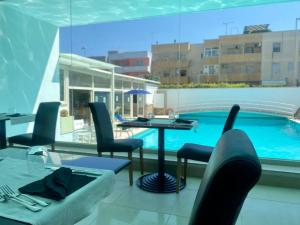 un patio con mesa y sillas junto a una piscina en Hotel Degli Haethey, en Otranto