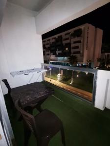 a table and a chair on a balcony at night at Appartement Corniche Nador in Nador