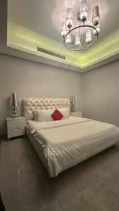 sypialnia z dużym białym łóżkiem z żyrandolem w obiekcie Seef manzil w mieście Seef