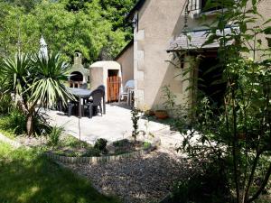 een patio met een zwarte tafel en stoelen in een tuin bij Gîte de la chênaie in Avrillé-les-Ponceaux