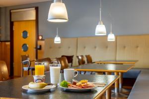 una mesa con platos de comida y vasos de zumo de naranja en Hotel Leipheim Süd, en Leipheim